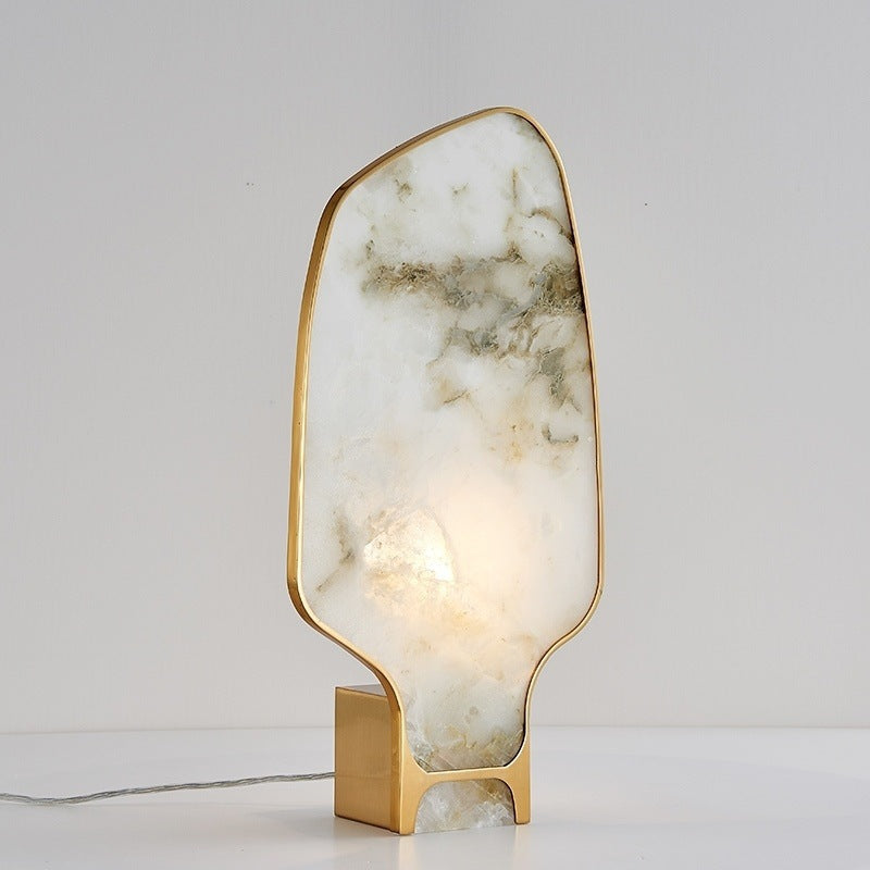 Front view of organic white marble and brass table lamp illuminated