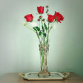 Ornate brass and glass flute vase holding red roses on a tray