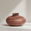 Front view of patterned terracotta orb vase on white background