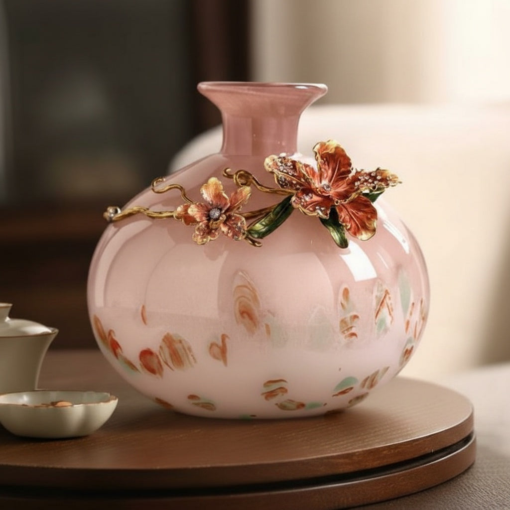 Pink glass vase with floral metal branch on table