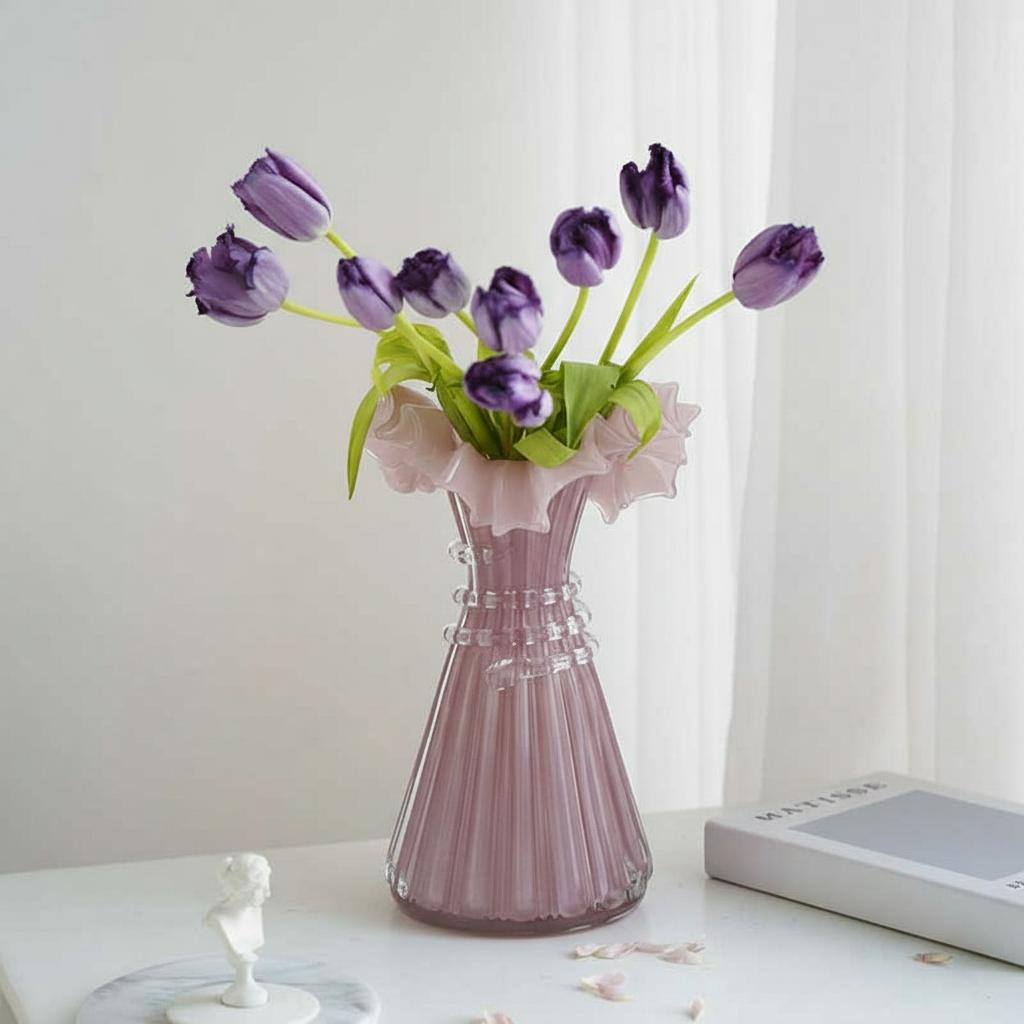 Pink fluted glass vase with purple tulips on table