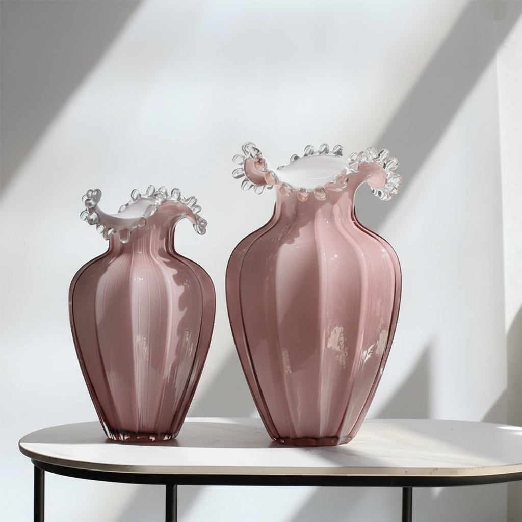 Set of two pink glass ruffled vases on table