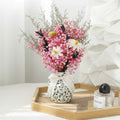 Pink gypsophila floral arrangement in patterned ceramic vase on wooden tray