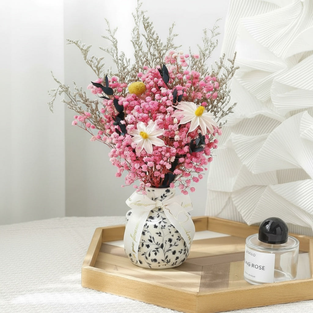 Pink gypsophila floral arrangement in patterned ceramic vase on wooden tray