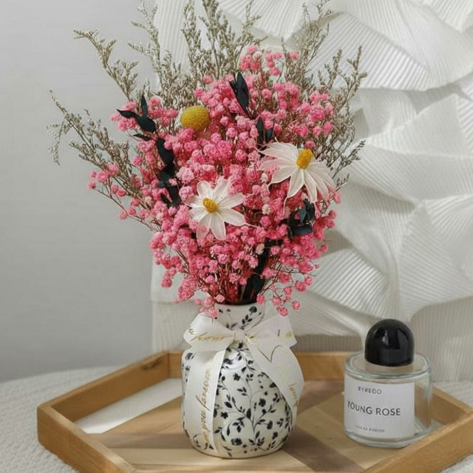 Front view of pink dried flower bouquet in black and white ceramic vase