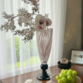 Pink swirl glass pedestal vase with floral arrangement on table