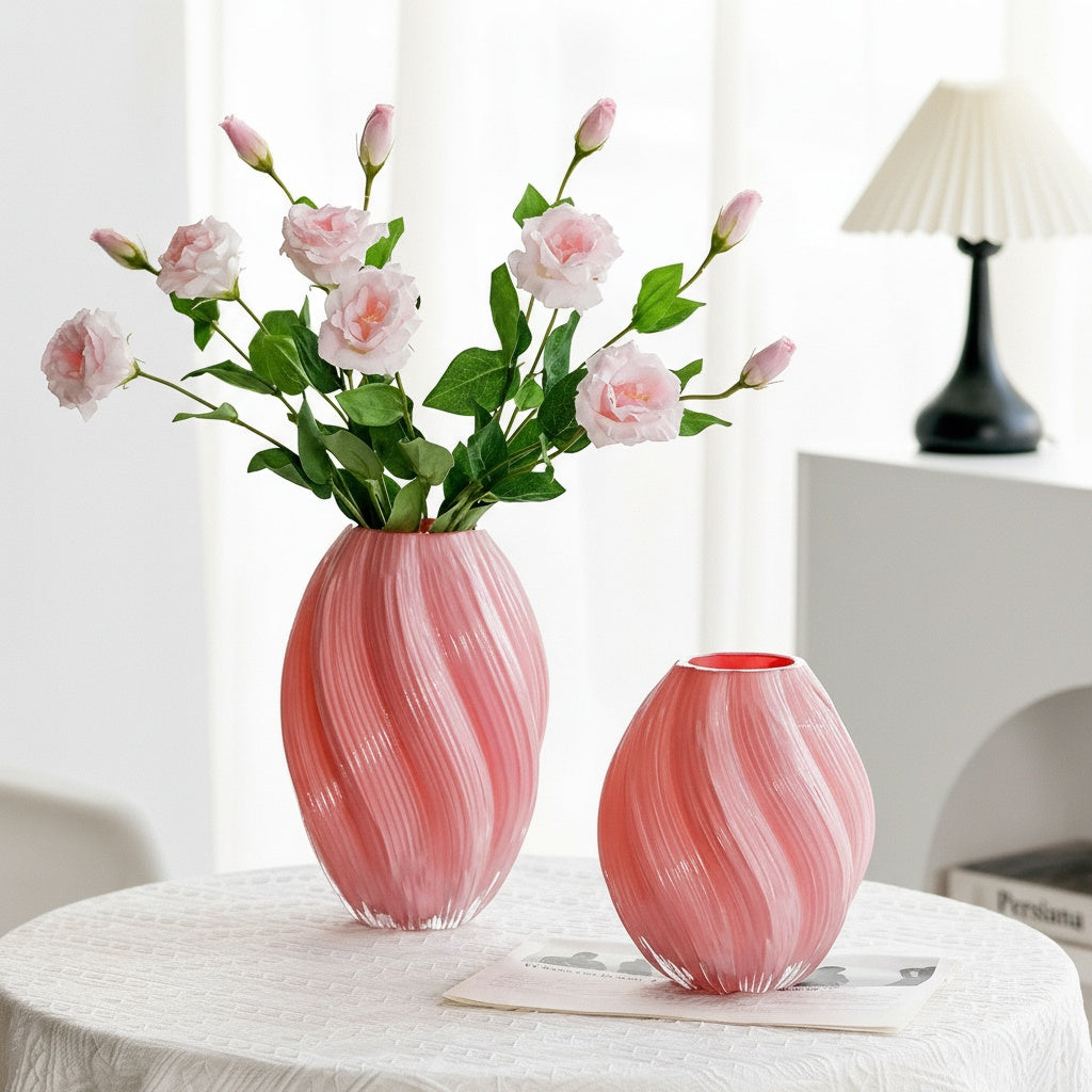 Pink swirled glass vase with flowers on table