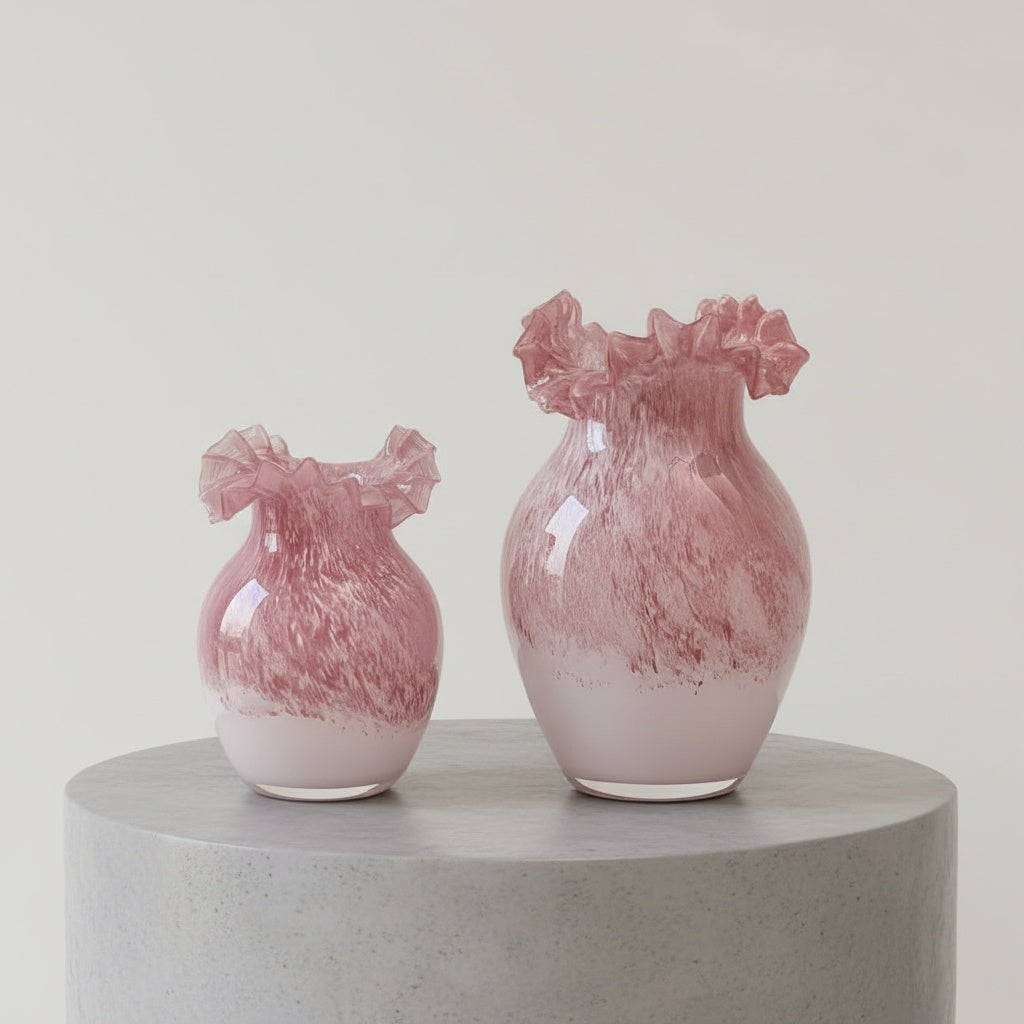 Pink and white gradient glass vase with ruffled rim on wooden table