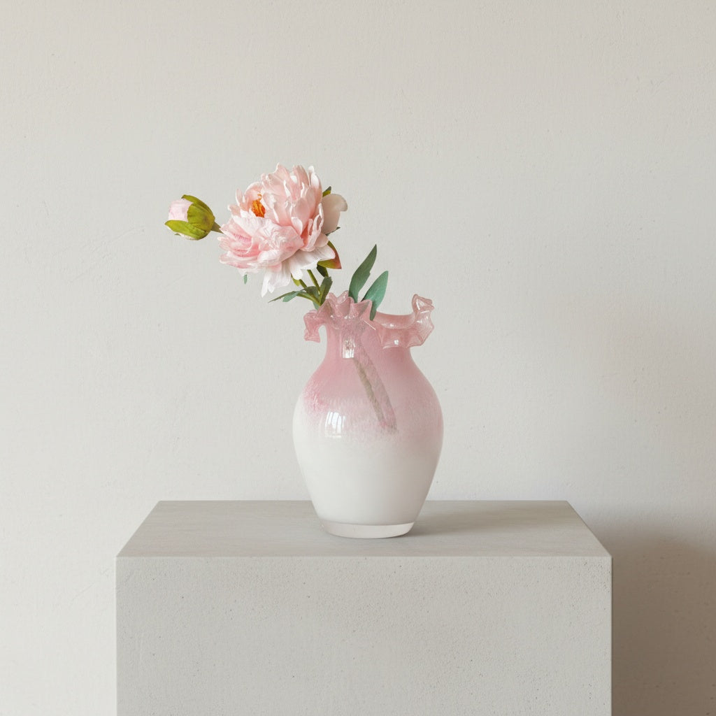 Ruffled pink glass vase with flower arrangement on coffee table