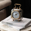 Front view of polished brass and silver square desk clock on books