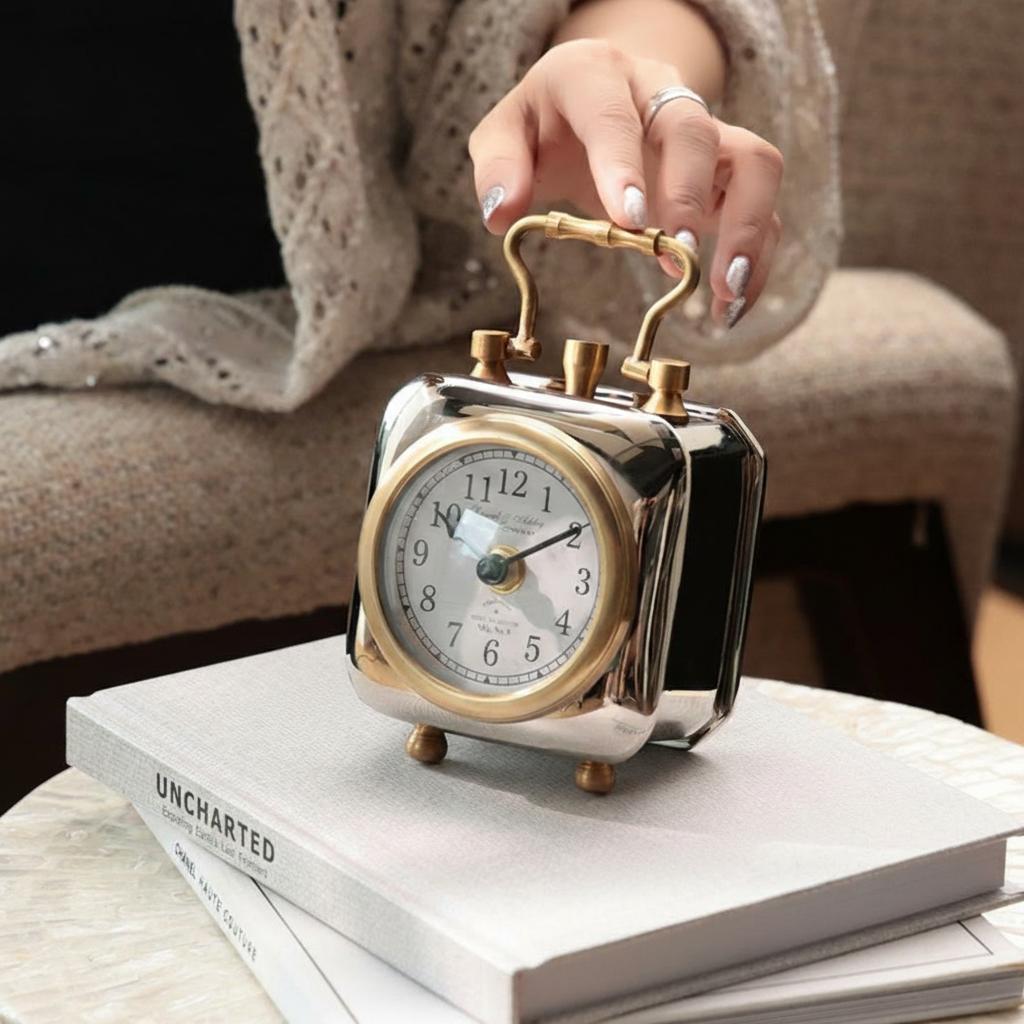 Hand holding the handle of the two-tone brass desk clock