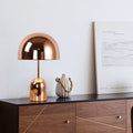 Polished copper dome table lamp on sideboard