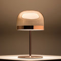 Polished copper table lamp with glass dome shade illuminated