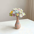 Porcelain floral bouquet in textured ceramic vase front view