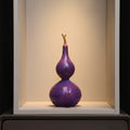 Purple resin gourd sculpture with gold stem on shelf