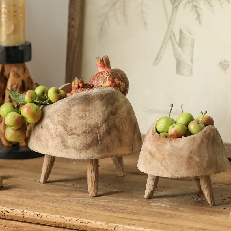 Close up of large and small wooden footed vessels filled with seasonal fruit showing raw wood texture