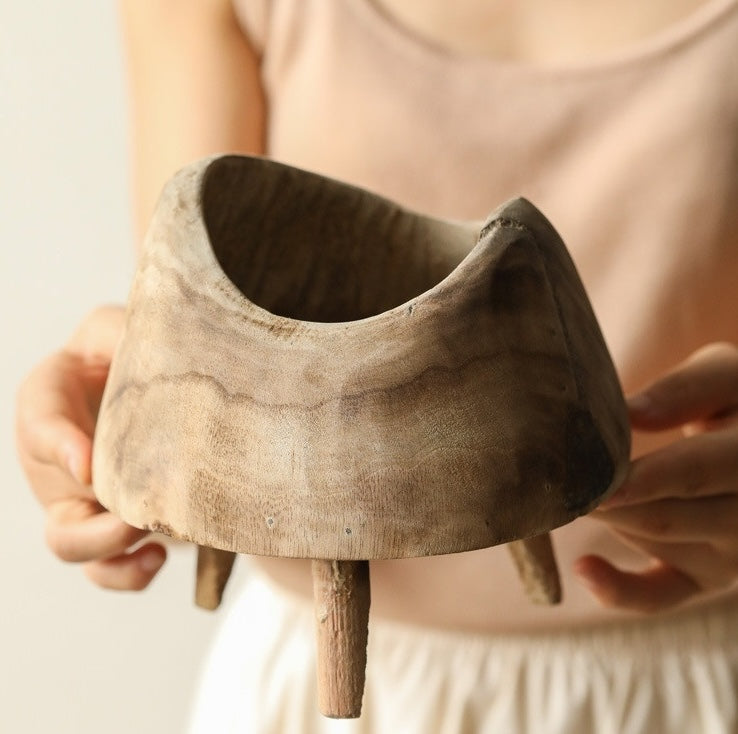 Hands holding the large raw wood footed bowl to demonstrate scale and texture