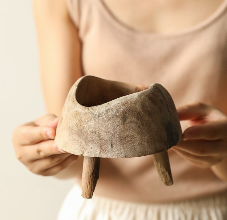 Hands holding the small raw wood footed bowl to demonstrate scale and handcrafted detail