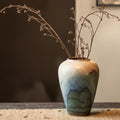 Medium ceramic vase styled with branches in a rustic setting