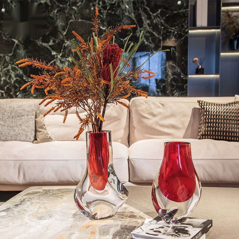 Red and clear art glass vase on marble coffee table with dried flowers