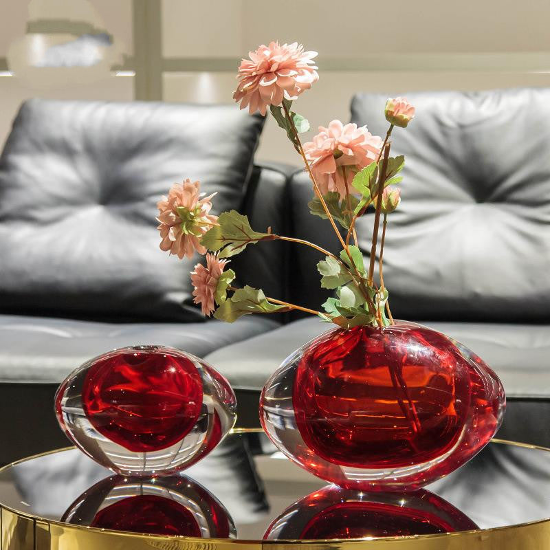 Red and clear glass vase with pink flowers on table