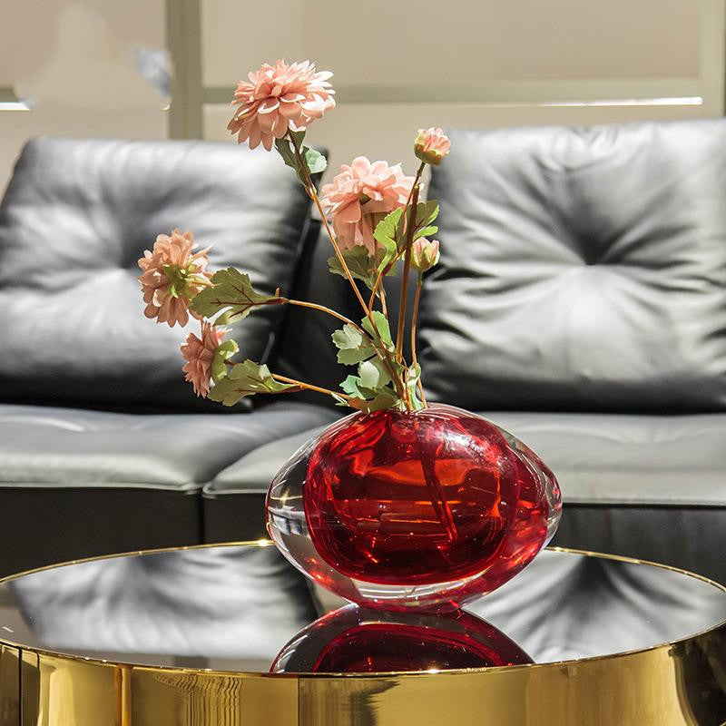 Side view of red oval art glass vase with floral arrangement