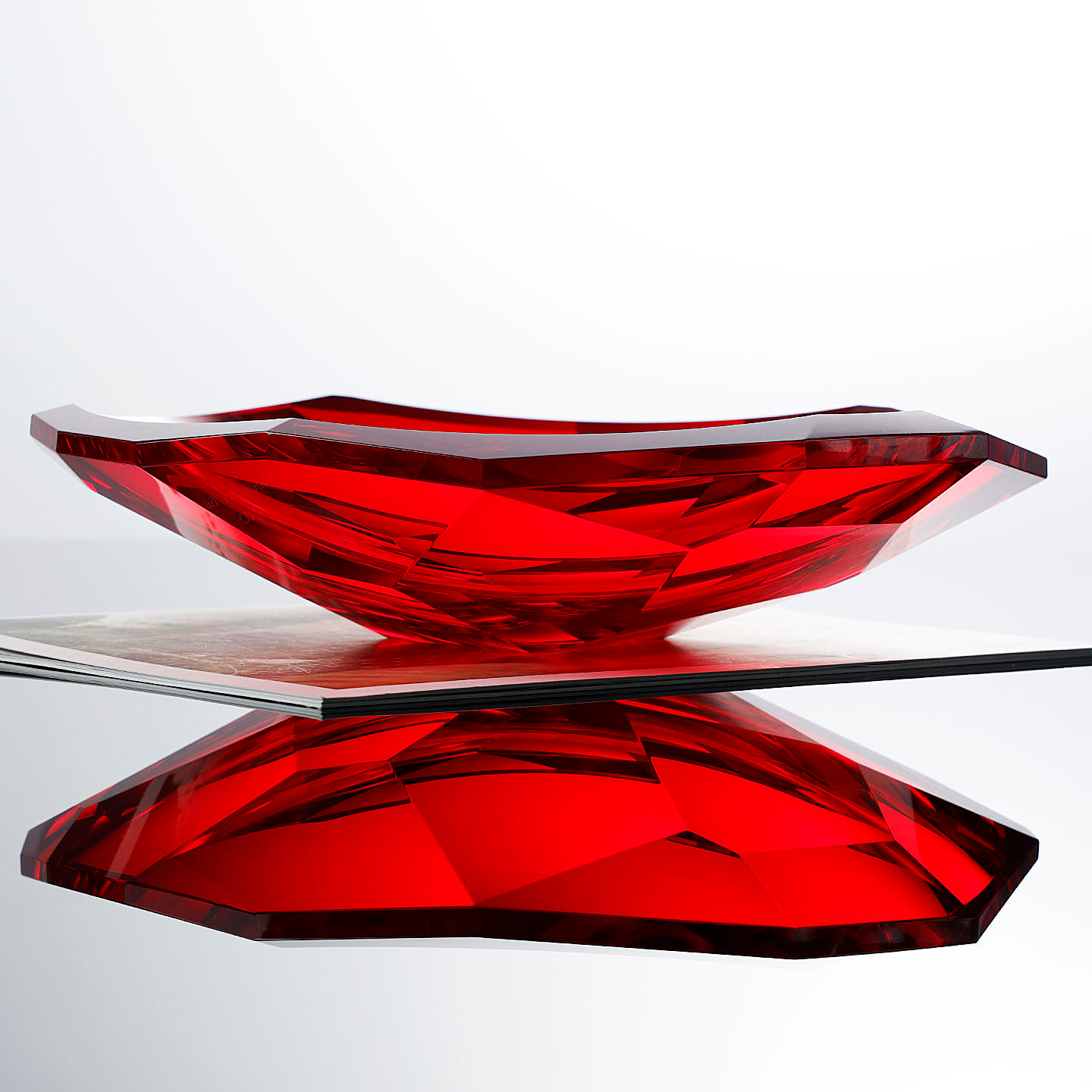 Side view of geometric red glass bowl on magazine
