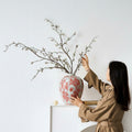 Woman styling branches in red floral porcelain vase