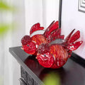 Front view of red glass goldfish sculpture on black shelf