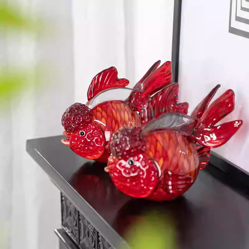 Front view of red glass goldfish sculpture on black shelf
