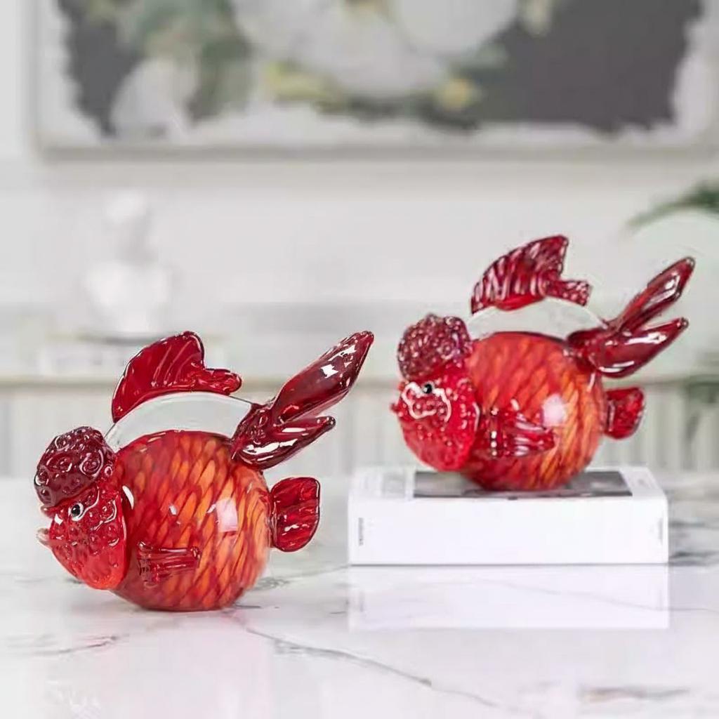 Pair of red glass goldfish sculptures on marble table
