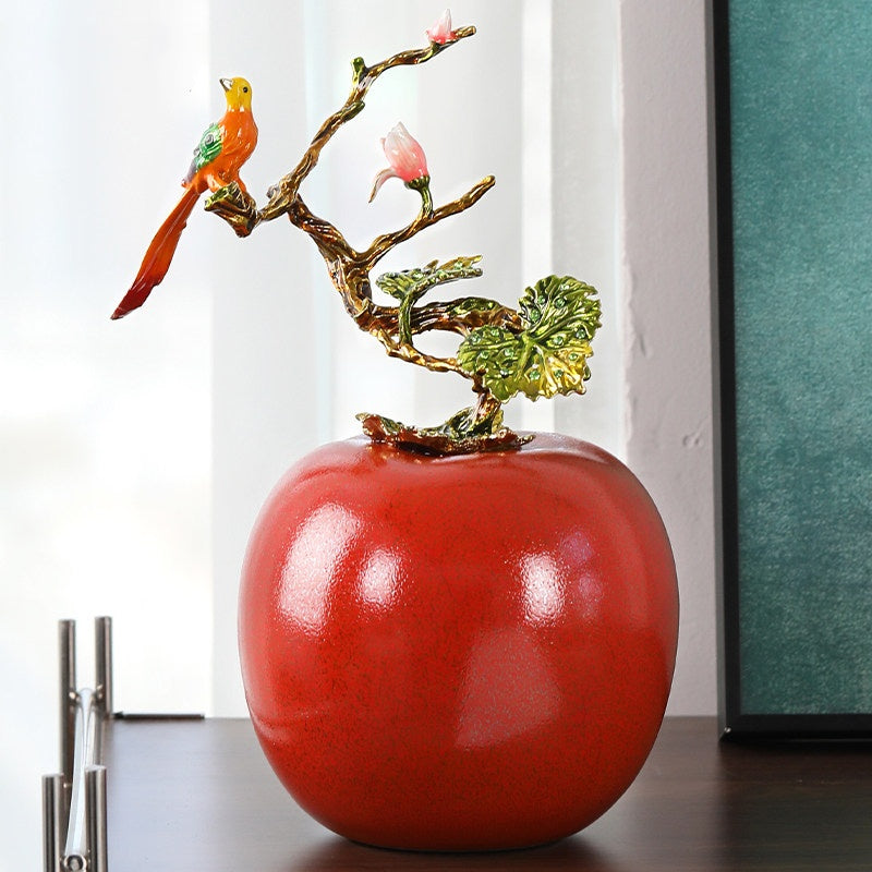 Red glazed ceramic apple sculpture with metal bird branch front view