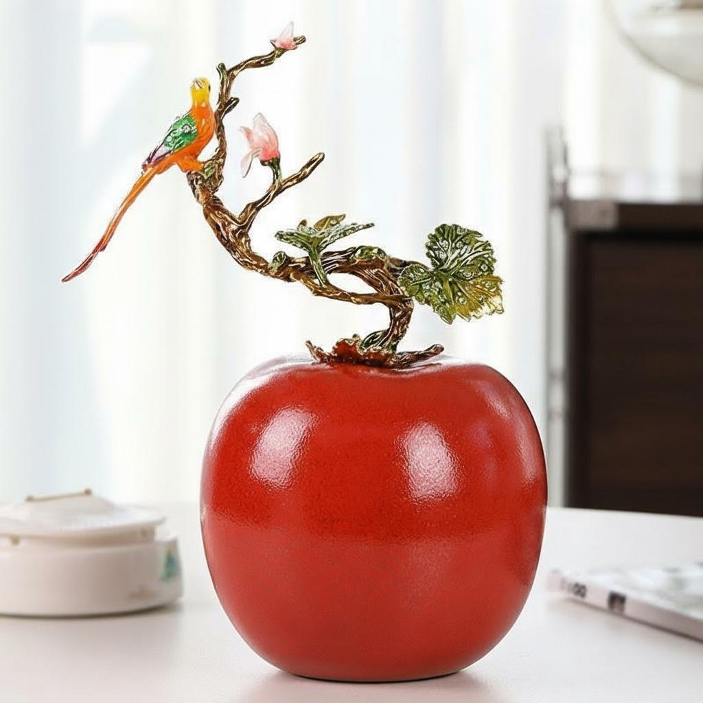 Detailed view of red apple sculpture with enameled bird and leaves
