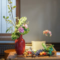 Red glazed ceramic vase with floral arrangement on table
