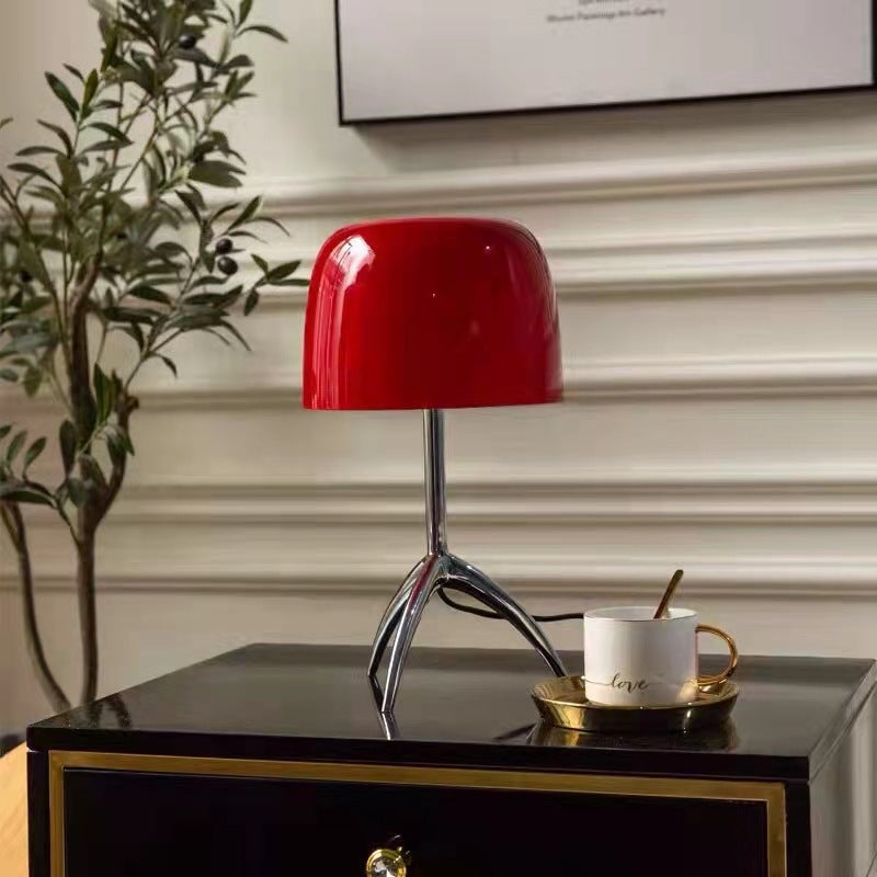 Red gloss dome shade table lamp with polished chrome tripod base on black side table