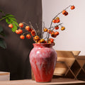 Red ceramic vase styled with branches on table