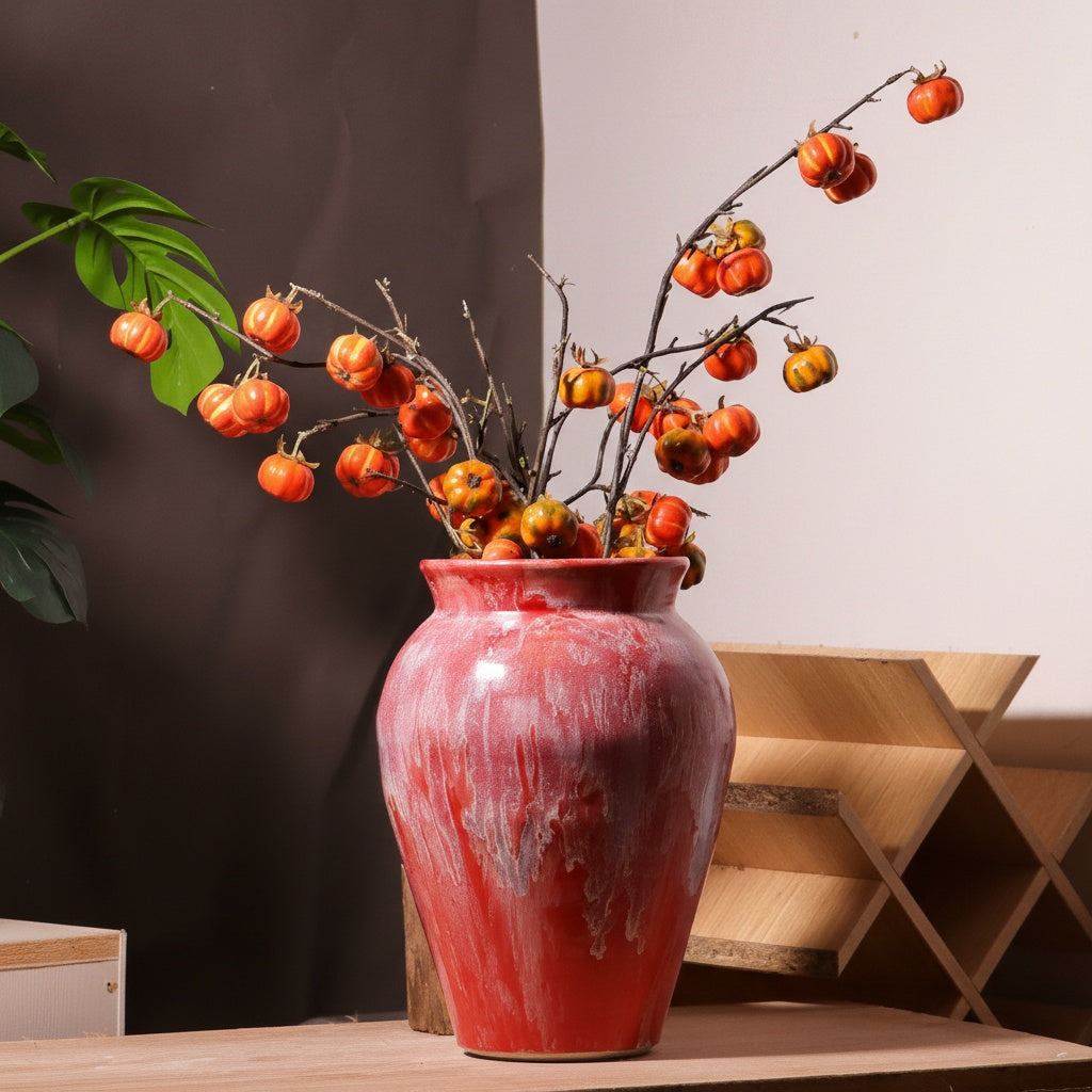 Red ceramic vase styled with branches on table