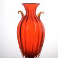 Full front view of red ribbed glass amphora vase with amber handles