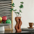 Red sandstone finish wavy cutout vase on table with fruit