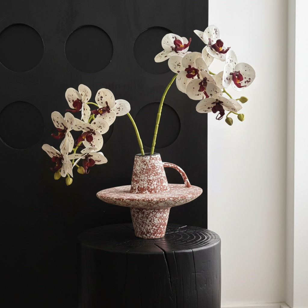 Red speckled ceramic geometric handled vase with orchids