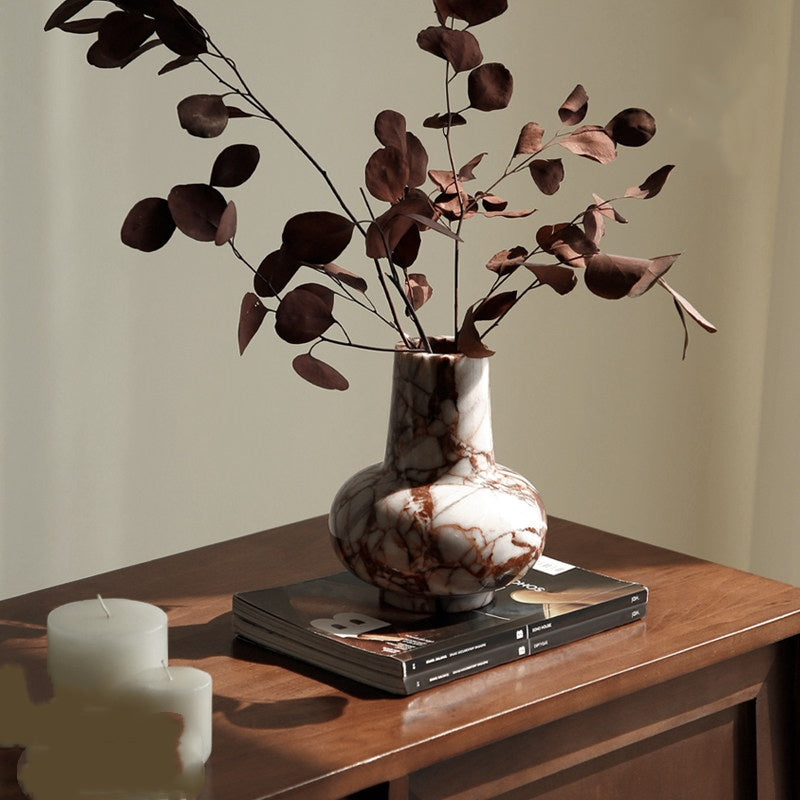 Lifestyle shot of marble vase with dried leaves on wooden table