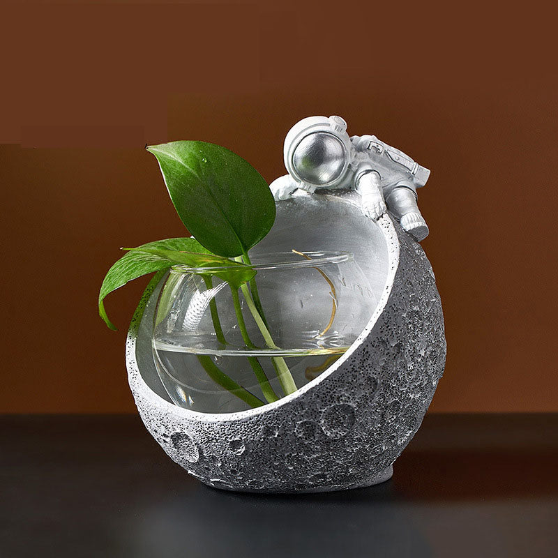 Silver astronaut moon bowl with plant on dark table