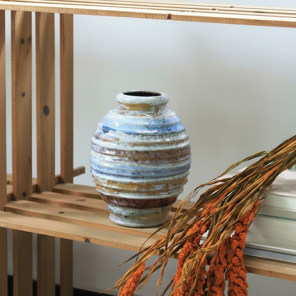 Empty ribbed stoneware vase on wooden shelf