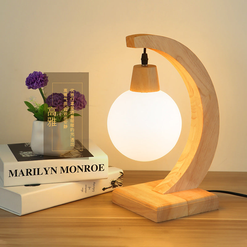 Lifestyle shot of wood crescent lamp on desk with books