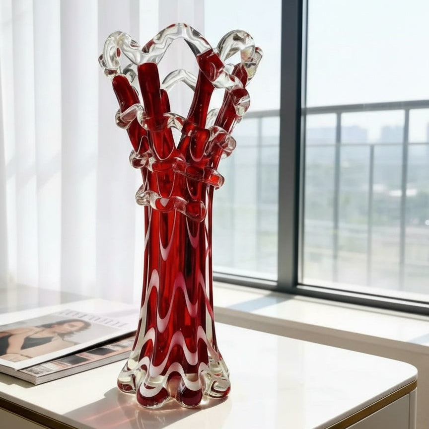 Front view of the ruby red and clear art glass wavy vase on a white table