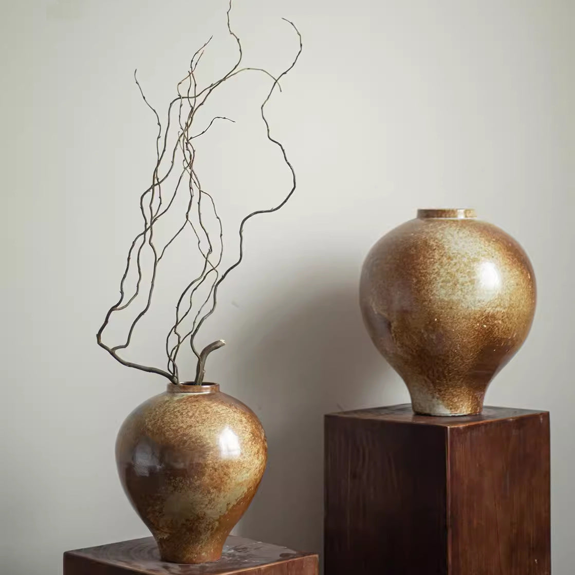Pair of rustic bronze vases displayed on wooden pedestals