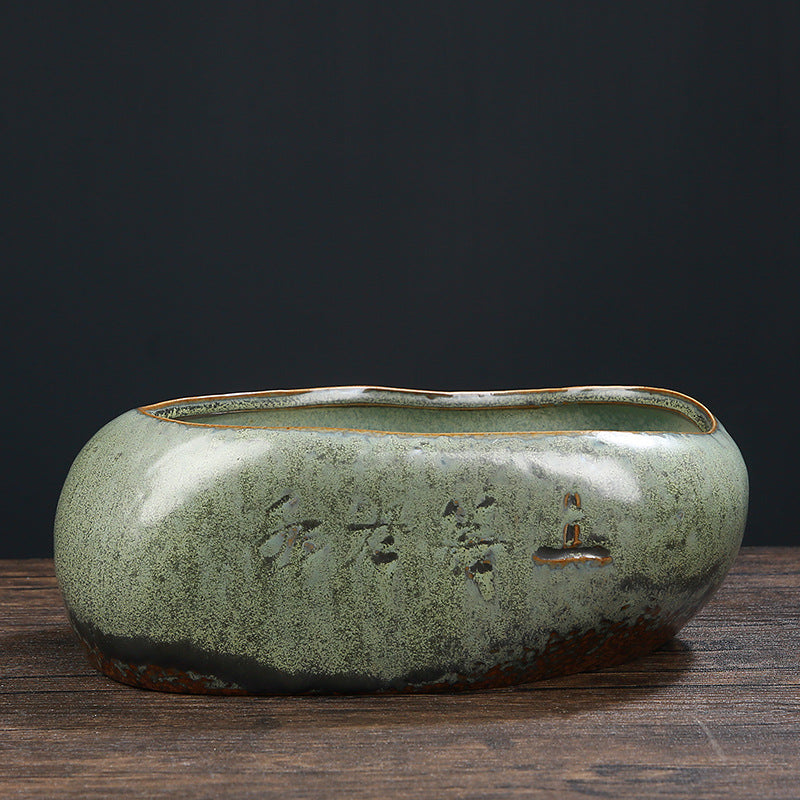 Side view of textured green ceramic vessel with calligraphy