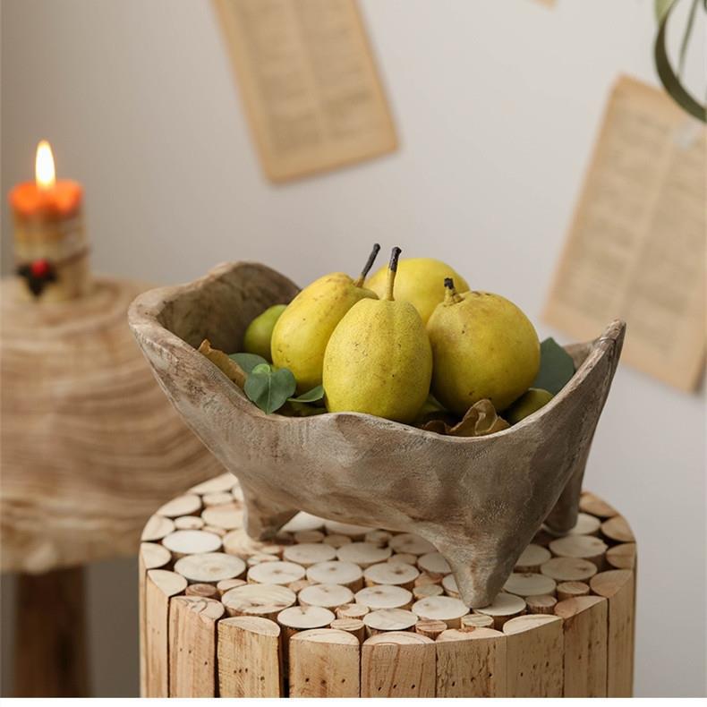 Side view of rustic wooden dough bowl on log stump holding yellow pears