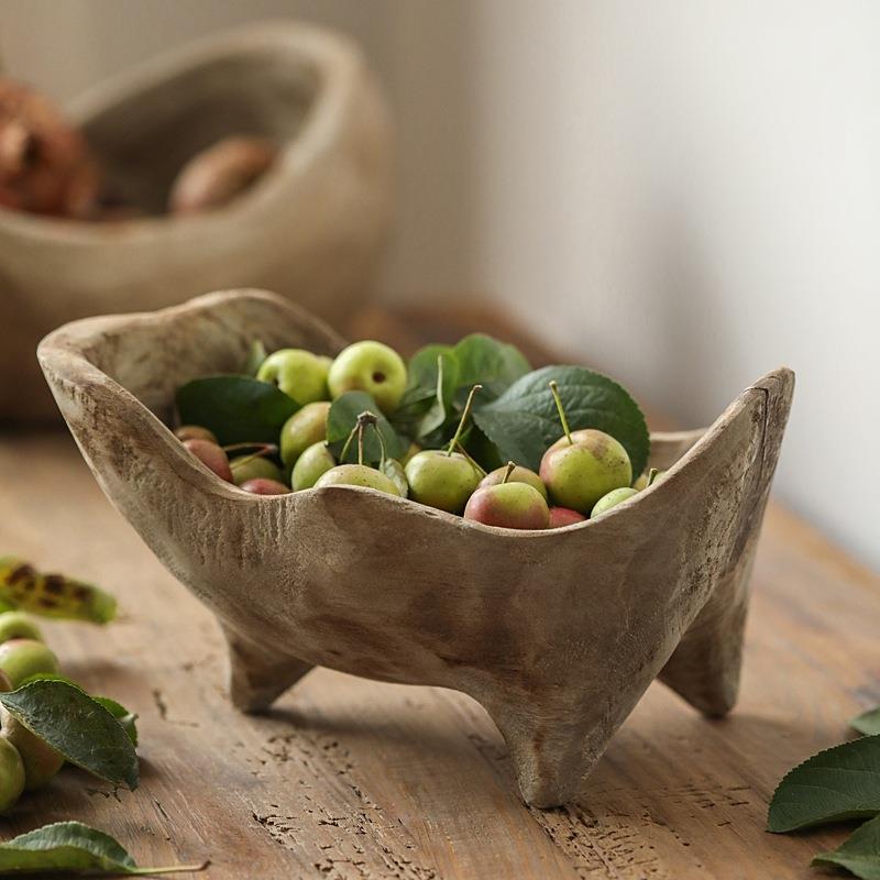 Rustic wooden fruit bowl filled with small green apples on a wooden table