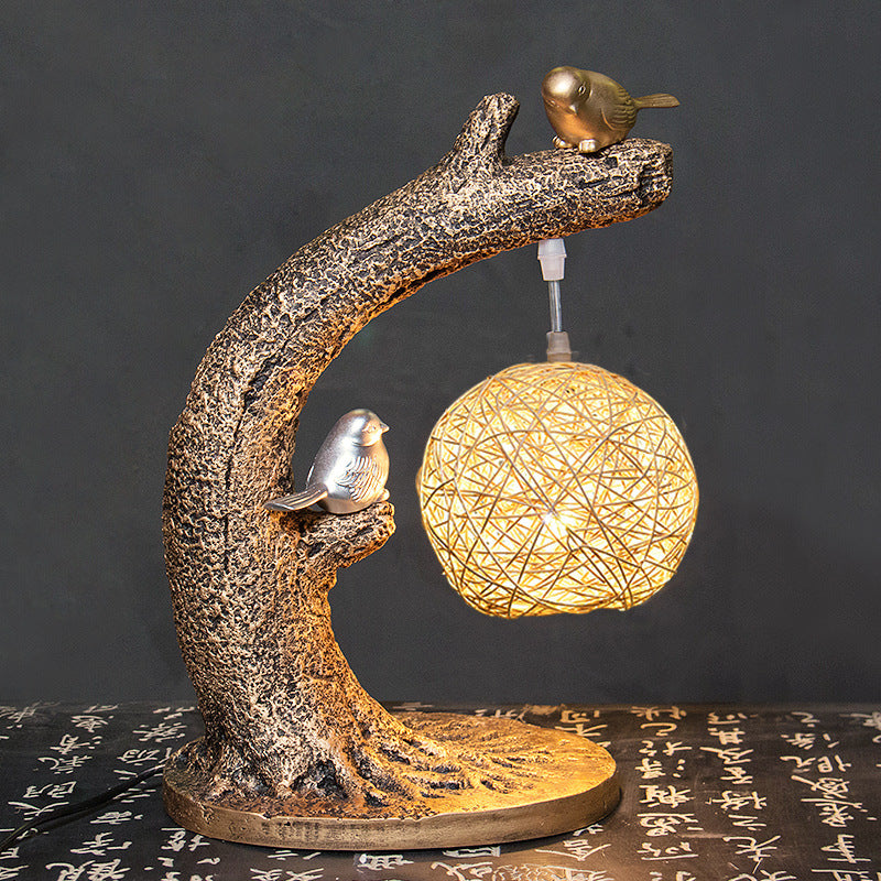 Front view of lit tree branch lamp with birds